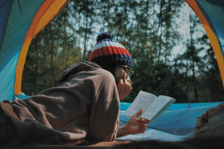 Traveler reading book in tent