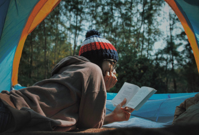 Traveler reading book in tent